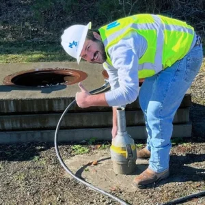 Concrete field technician performing fresh concrete testing with ACI field testing equipment at a construction site.