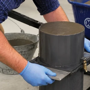 Technician preparing self-consolidating concrete in a testing mold during a laboratory procedure.