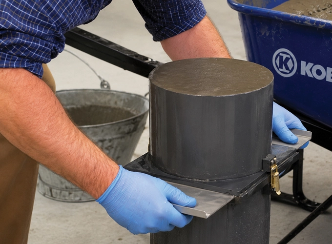 Technician preparing self-consolidating concrete in a testing mold during a laboratory procedure.